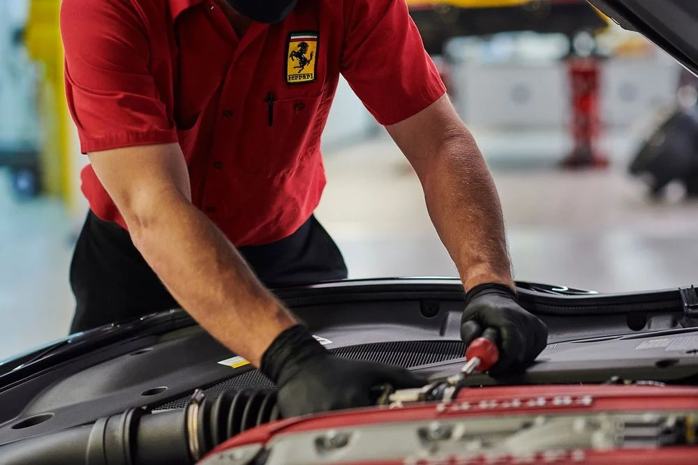 Ferrari technician performing maintenance under the hood