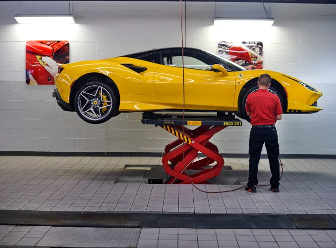 Yellow Ferrari raised on a professional service lift